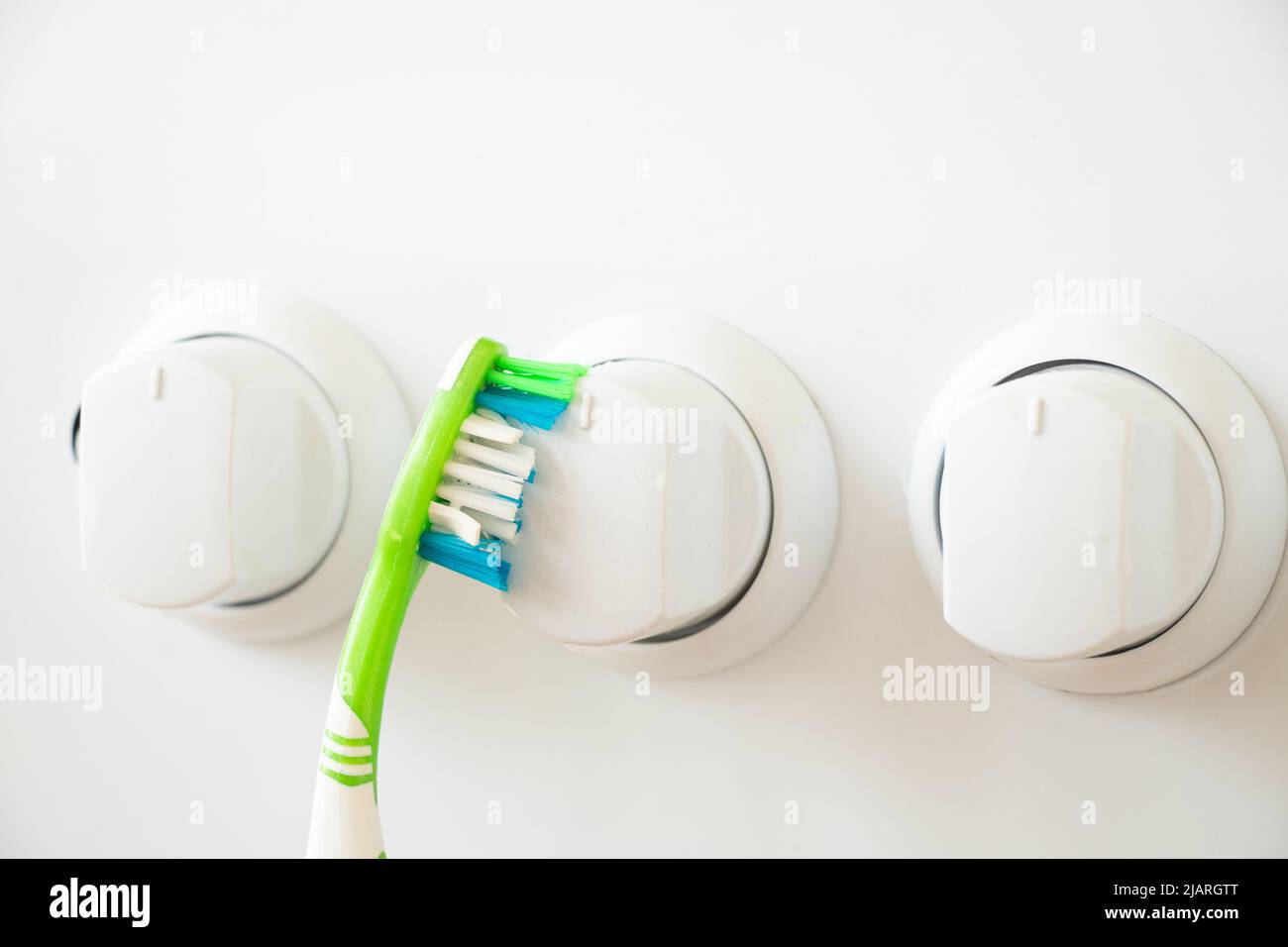 Toothbrush cleans the button on the gas stove from dirt ,cleaning and cleaning,wash the gas stove in the kitchen at home Stock Photo