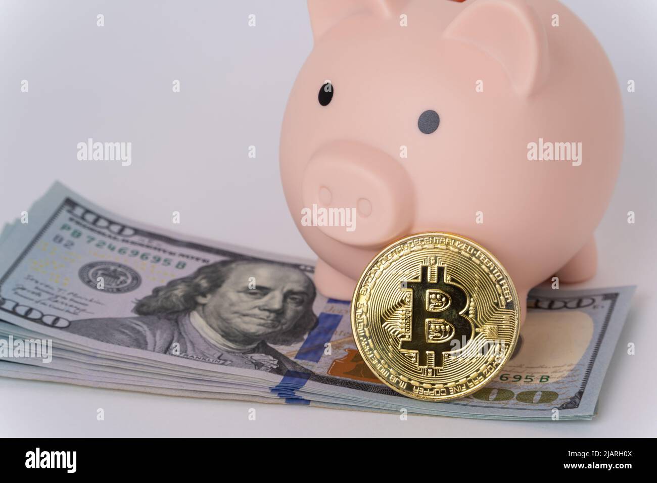 Piggy bank with dollars and a bitcoin coin on a white background. The concept of investing in bitcoin, safe trading, retirement savings, account secur Stock Photo