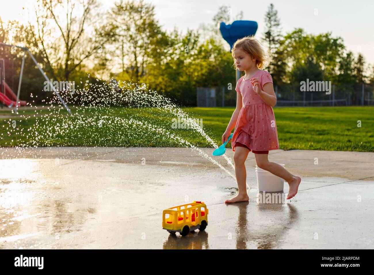 Small child playing at splash pad playground in summer. Water park with fountains for children. Summertime activities for kids Stock Photo