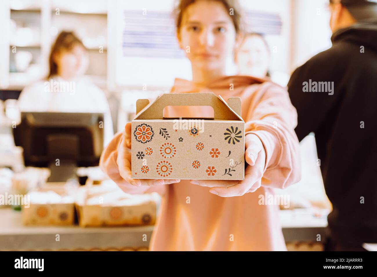 courier girl, parttime student, hands out takeaway dessert box to