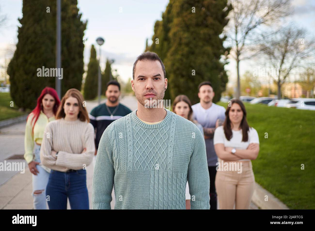 Man looking serious at the camera while standing in front of a group of people. Team and leadership concept. Stock Photo