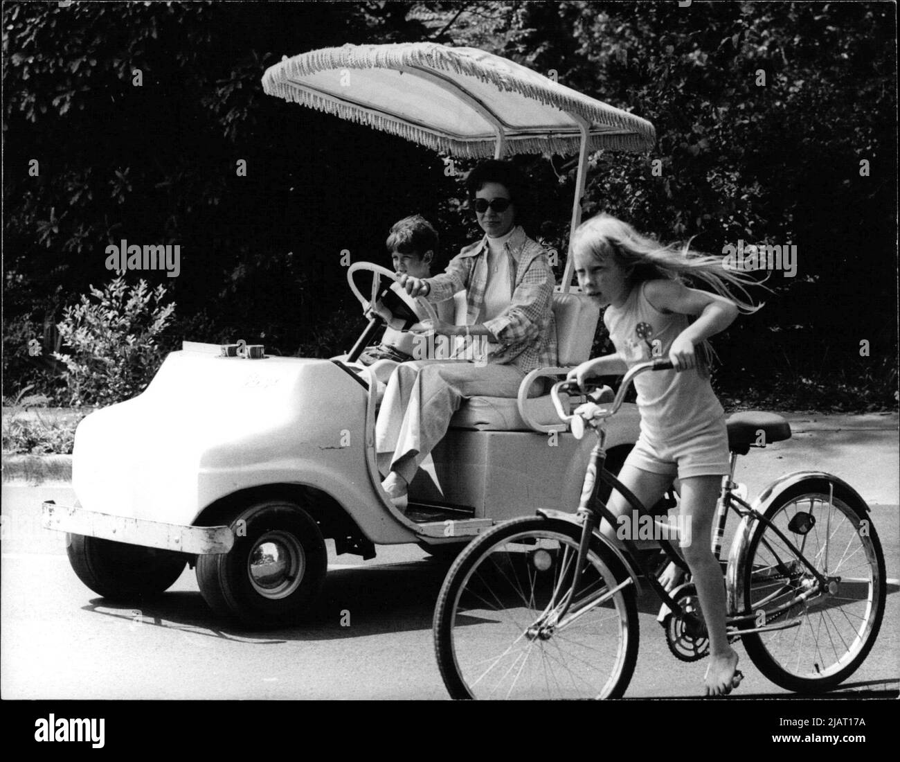 Das Bild zeigt Rosalynn Carter, die Ehefrau des US-Präsidenten Jimmy Carter, in einem Golfwagen mit einem Kind. Neben dem Auto fährt ihre Tochter Amy Carter auf einem Fahrrad. Stock Photo