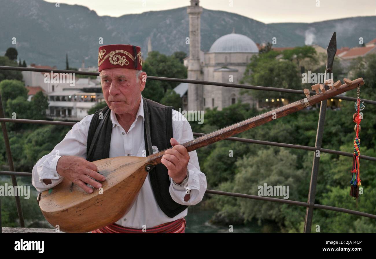 Mostar, Bosnia and Herzegovina – May 2022:  Man playing gusle on top of the old bridge. Bridge inscripted as a national monument and UNESCO world heri Stock Photo