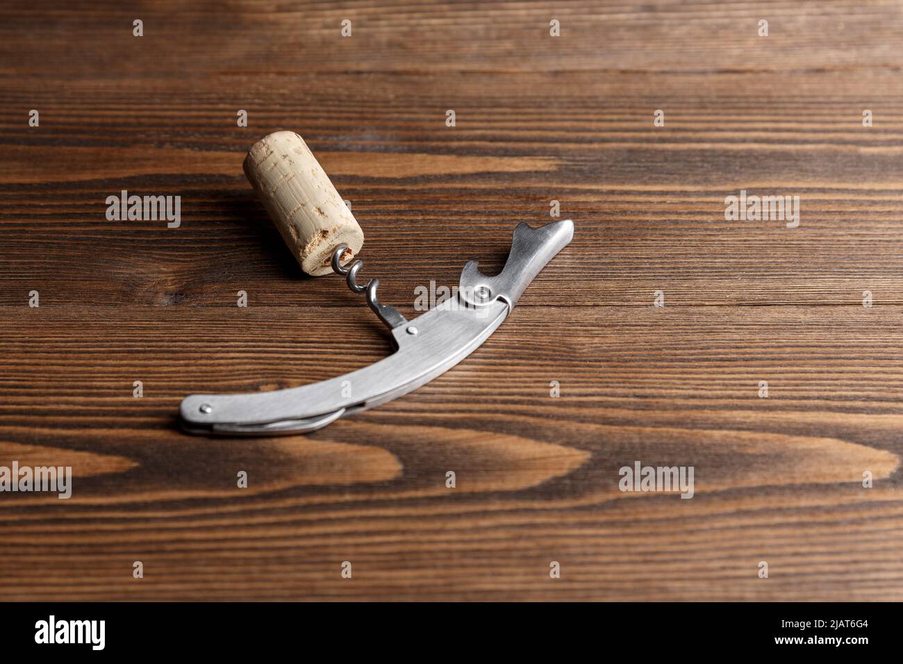 Stainless  wine corkscrew with a cork on a wooden background. Vine culture concept Stock Photo