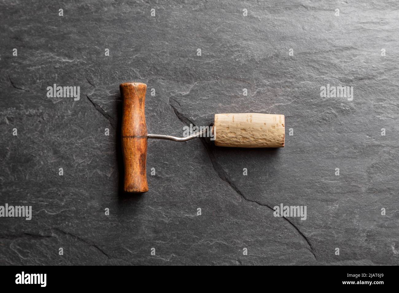 Vintage wine corkscrew in a cork of wine on a black slate background. Vine culture concept Stock Photo