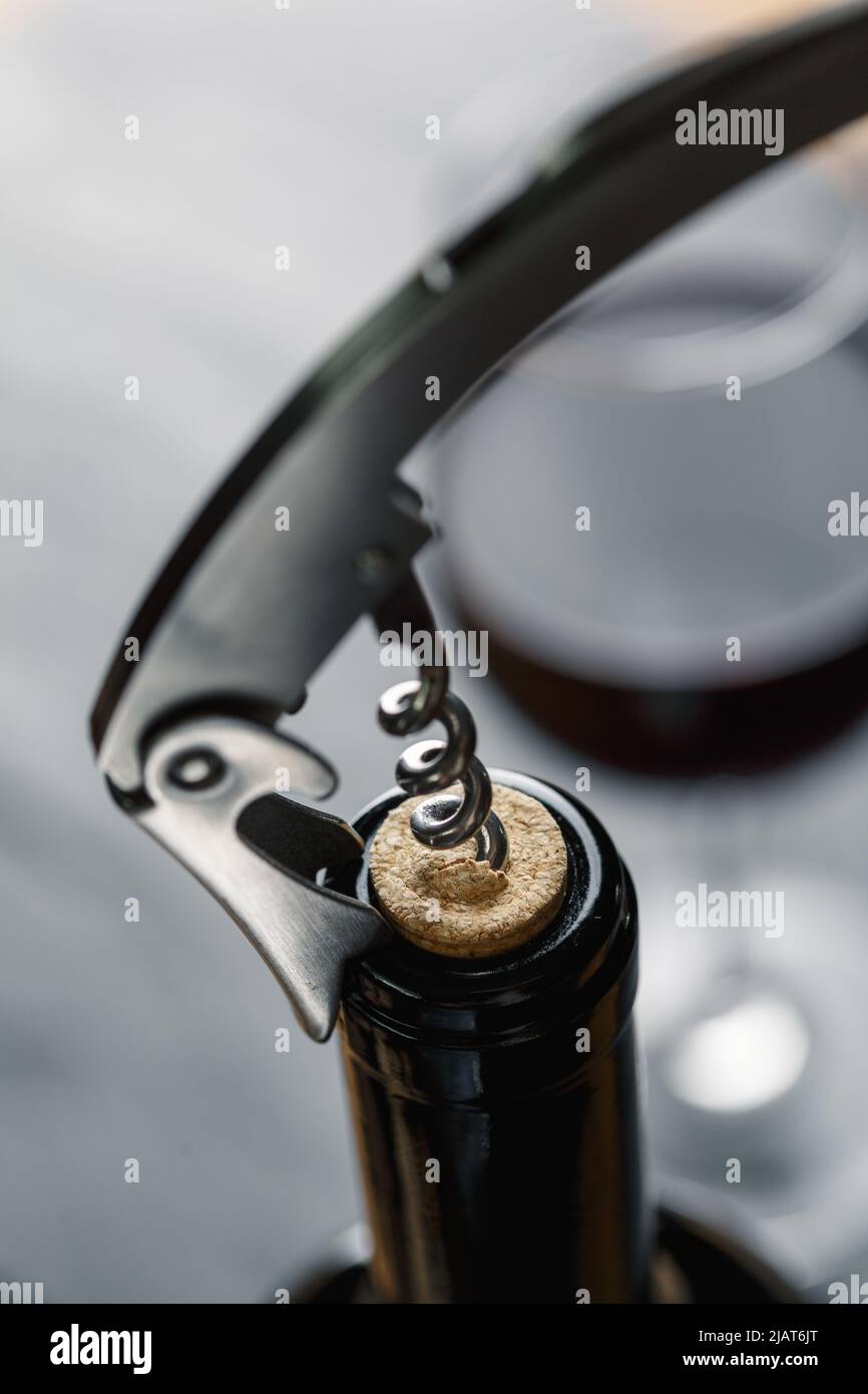 Stainless  wine corkscrew in a cork of wine bottle neck on a black rocky slate background. Vine culture concept Stock Photo