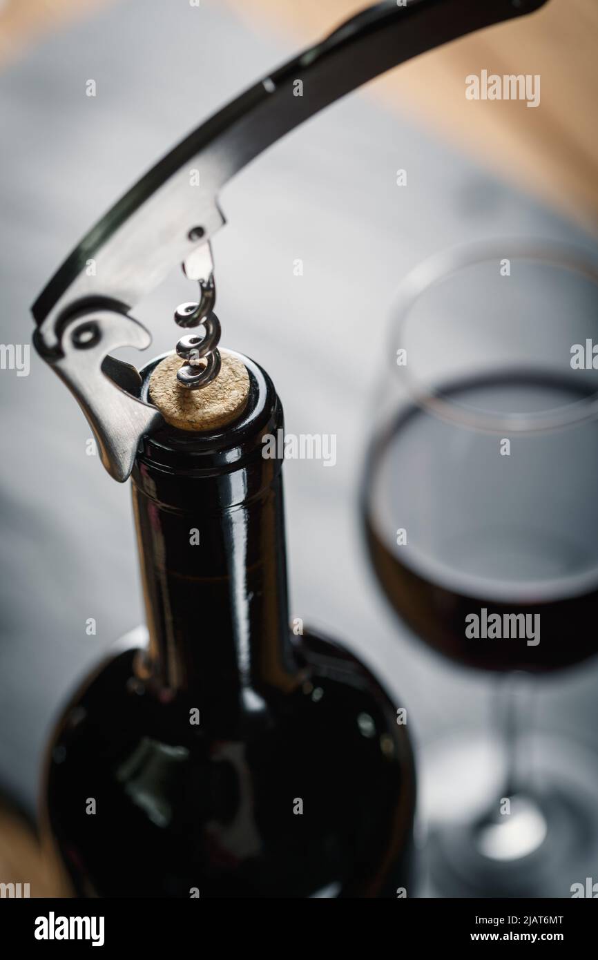 Stainless  wine corkscrew in a cork of wine bottle neck on a black rocky slate background. Vine culture concept Stock Photo