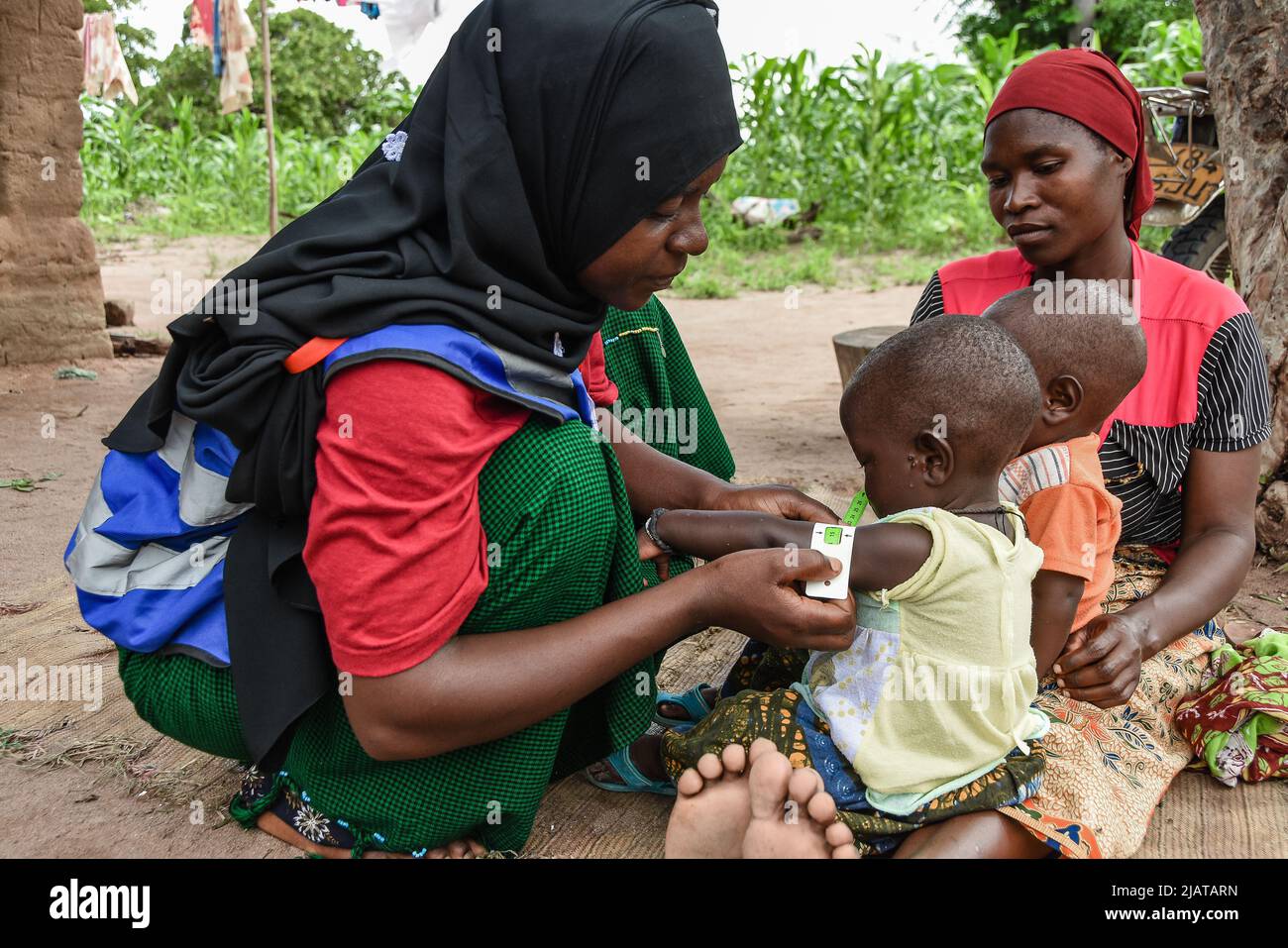 Community Health Worker measuring the level of malnutrition from the twins Faita and Khadija Mohamed at Samora village in Mtwara region, Tanzania Stock Photo