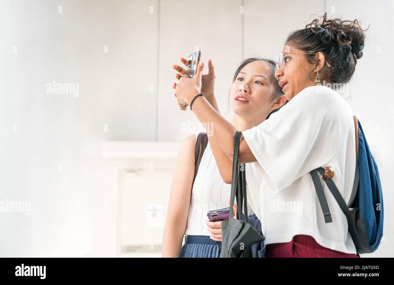 Two young women with different ethnicity looking at a smartphone together. Copy space. Stock Photo
