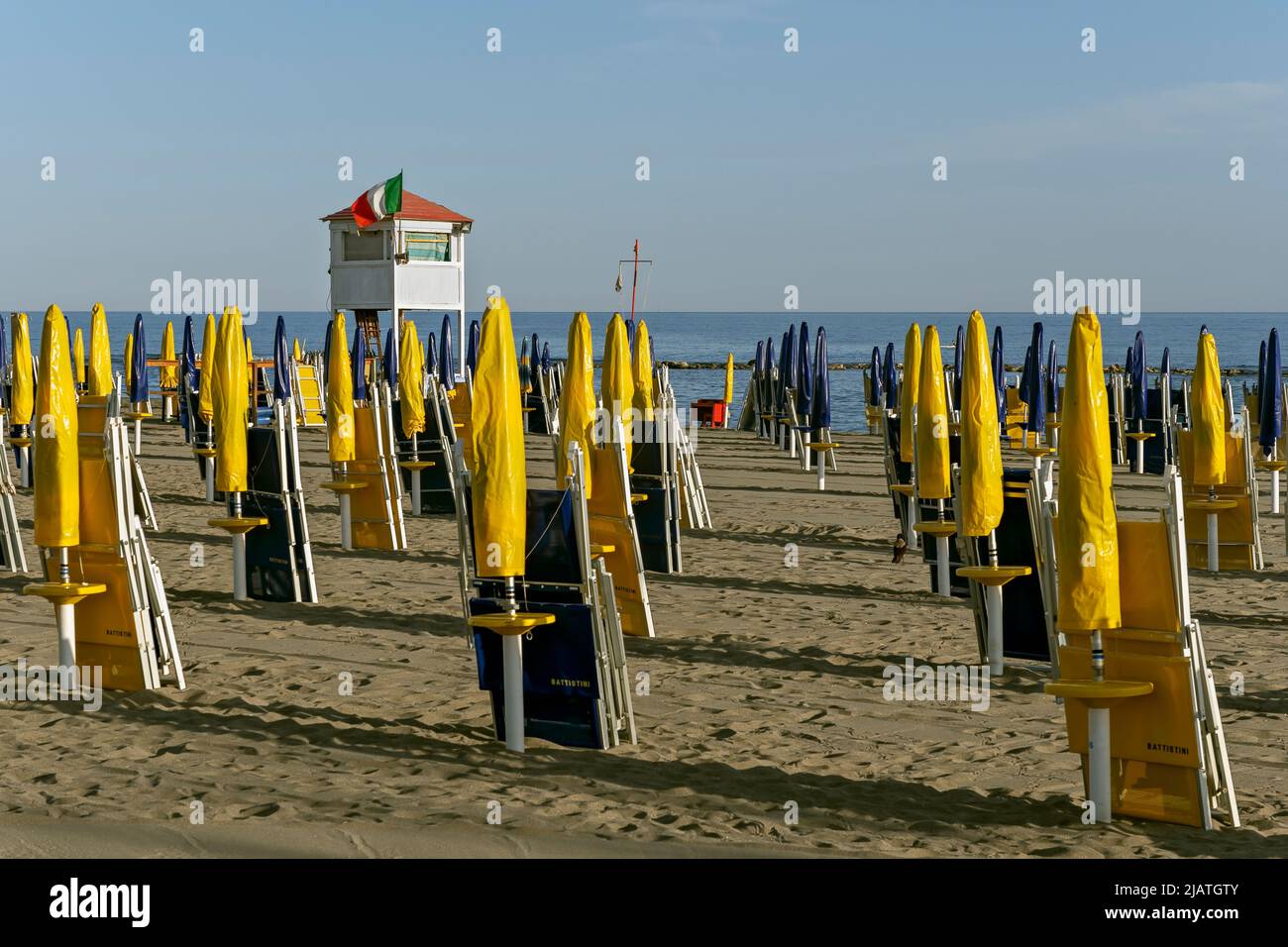 Lifeguard tower and lines of bright Yellow and Dark blue umbrellas and deckchairs on Ostia Beach, Rome, Italy, Europe, European Union, EU Stock Photo