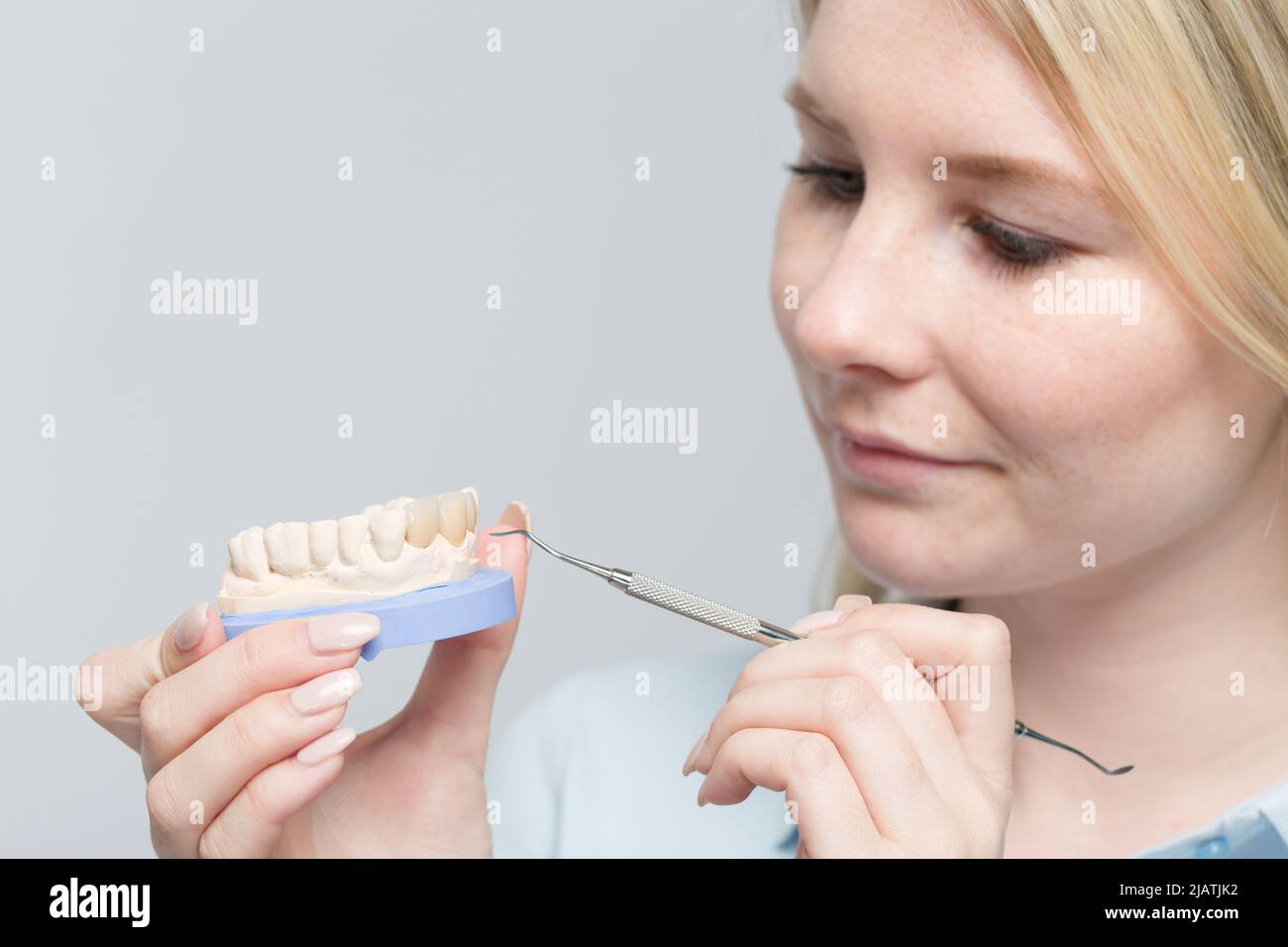 Young female dental technician works on denture parts in a dental