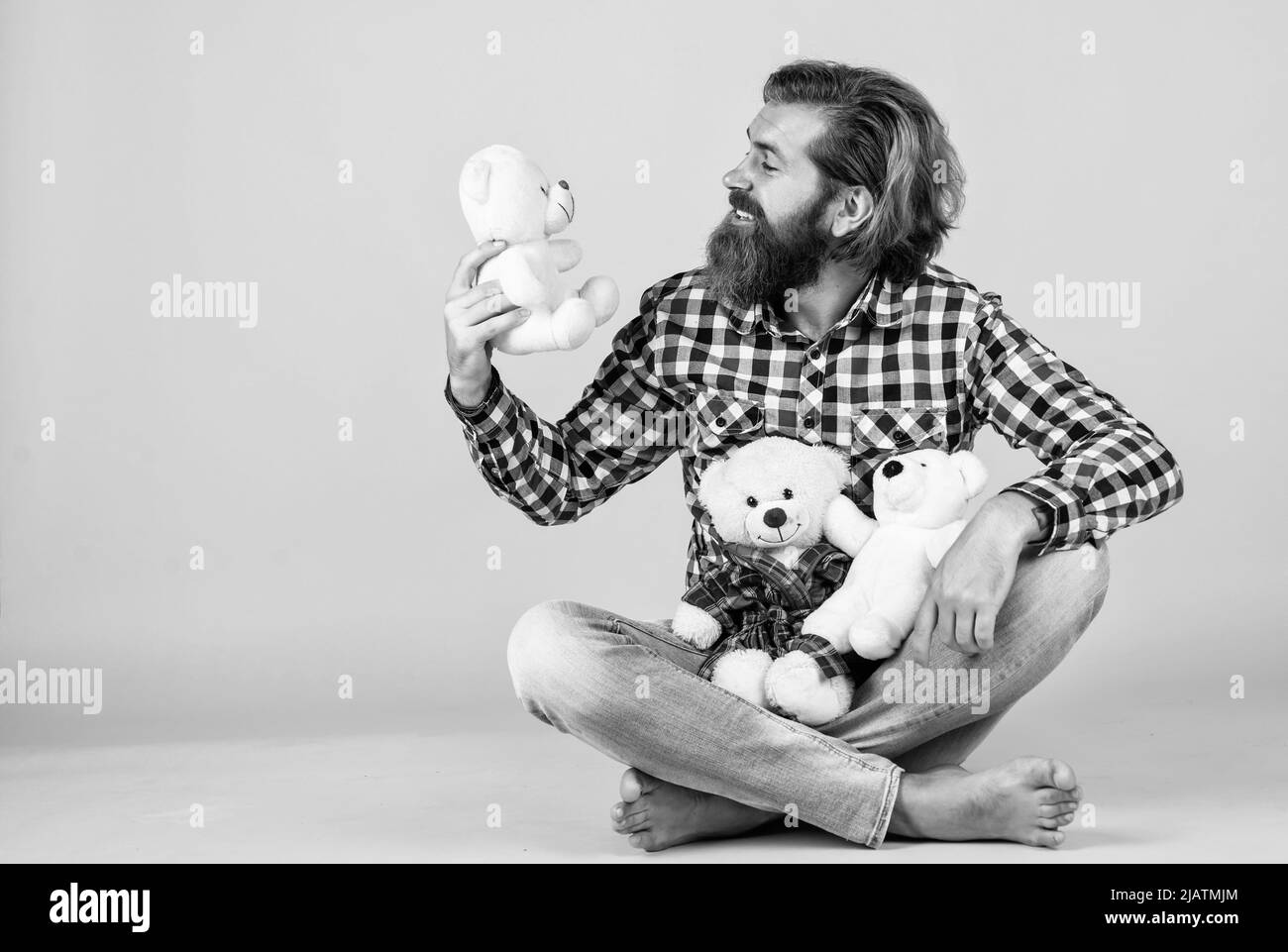 brutal bearded man wear checkered shirt having lush beard and moustache with teddy bear toy, toy shop Stock Photo