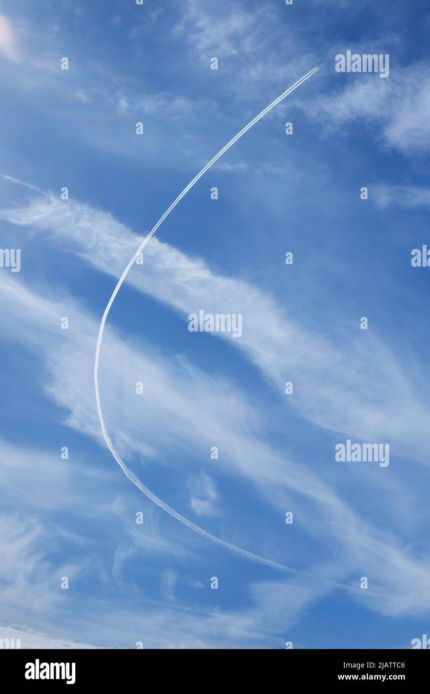 curving vapour trail on blue sky and white clouds Stock Photo