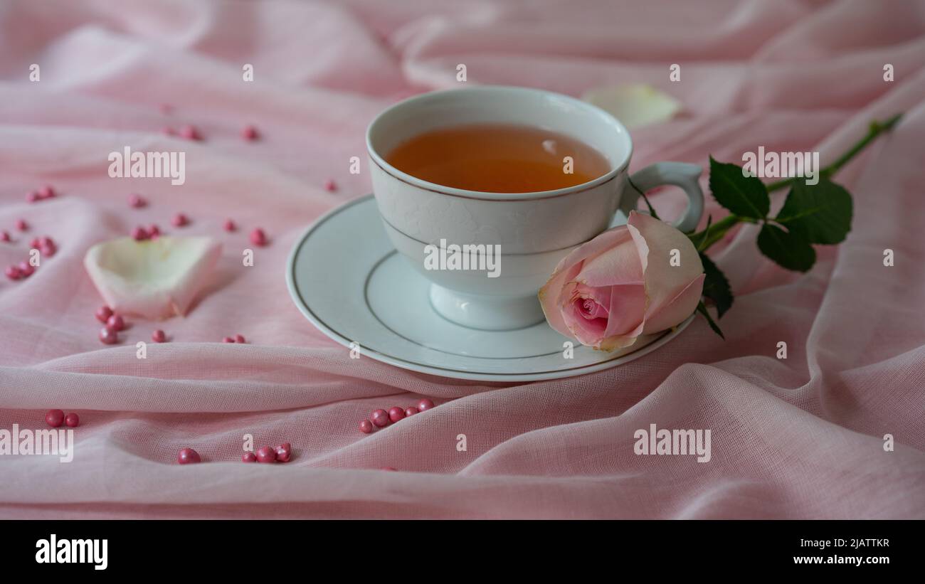 Eine Tasse Tee und ein Rosenstrauß auf rosa Hintergrund Stock Photo