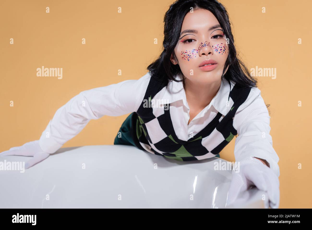 Trendy young asian model with glitter makeup looking at camera
