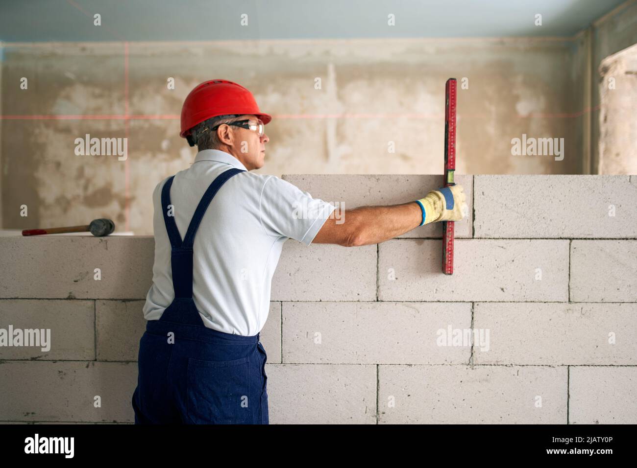 Bricklayer using spirit bubble and laser level to precise check