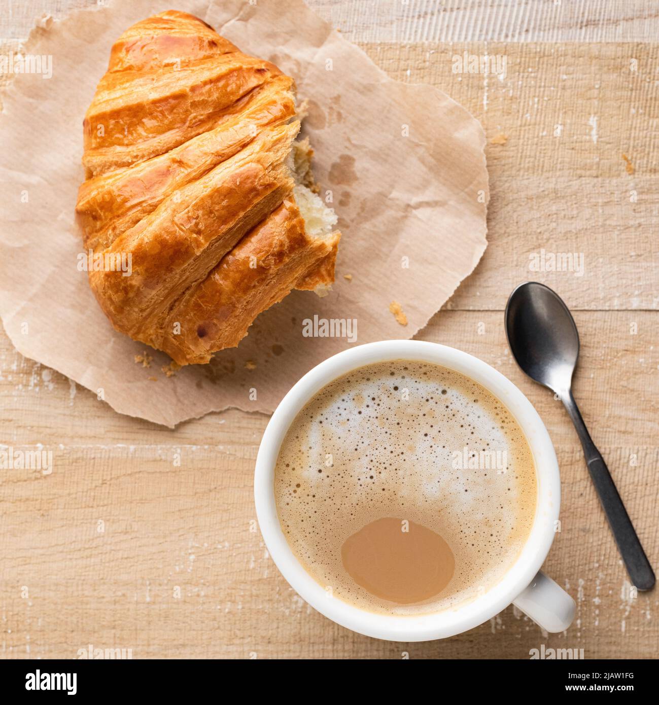 Cup of coffee and croissant on wooden table, top view. Breakfast in cafe or coffee break Stock Photo