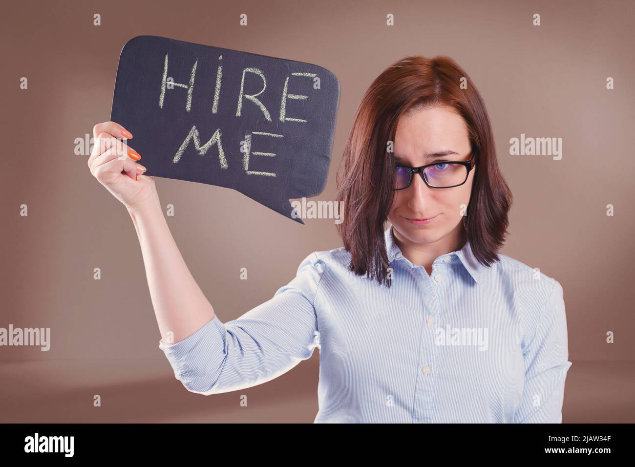 Woman in glasses with 'Hire me' text on the slate. Job search and hiring concept Stock Photo