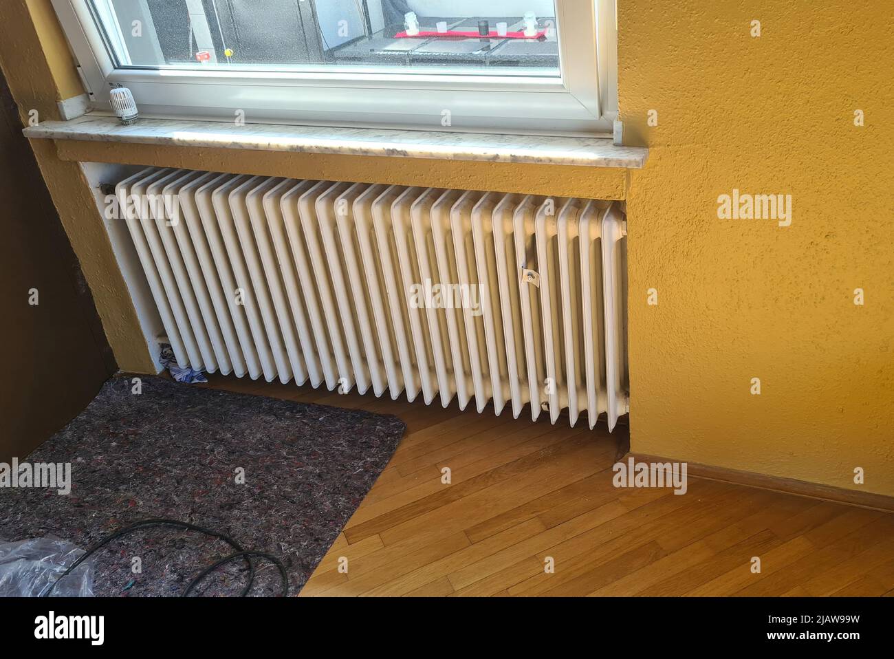 Dismantling a broken radiator in a private house. Radiator Stock Photo
