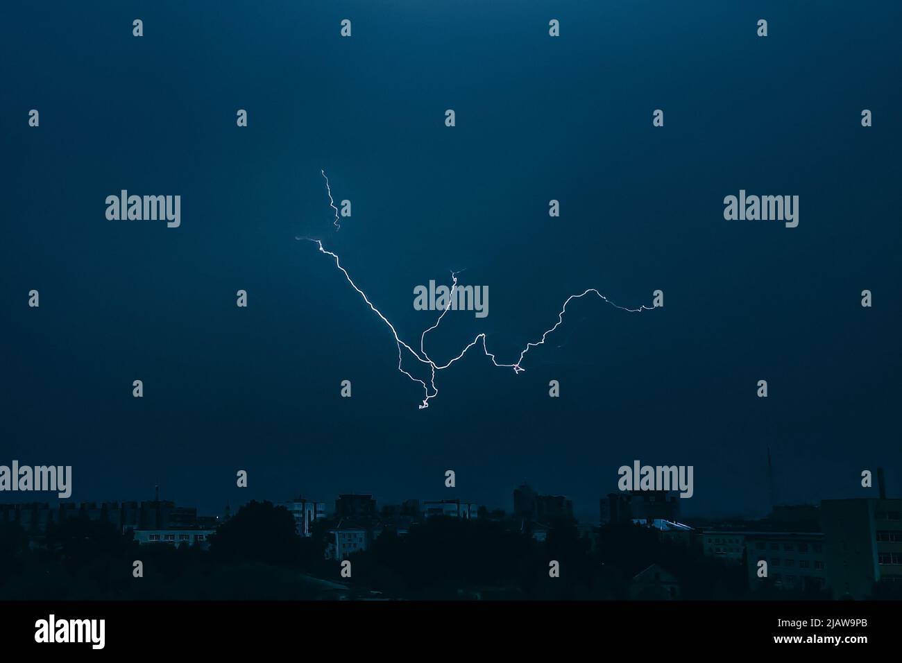 Lightning in sky over city. Bright flashes on dark night. Thunderclouds ...