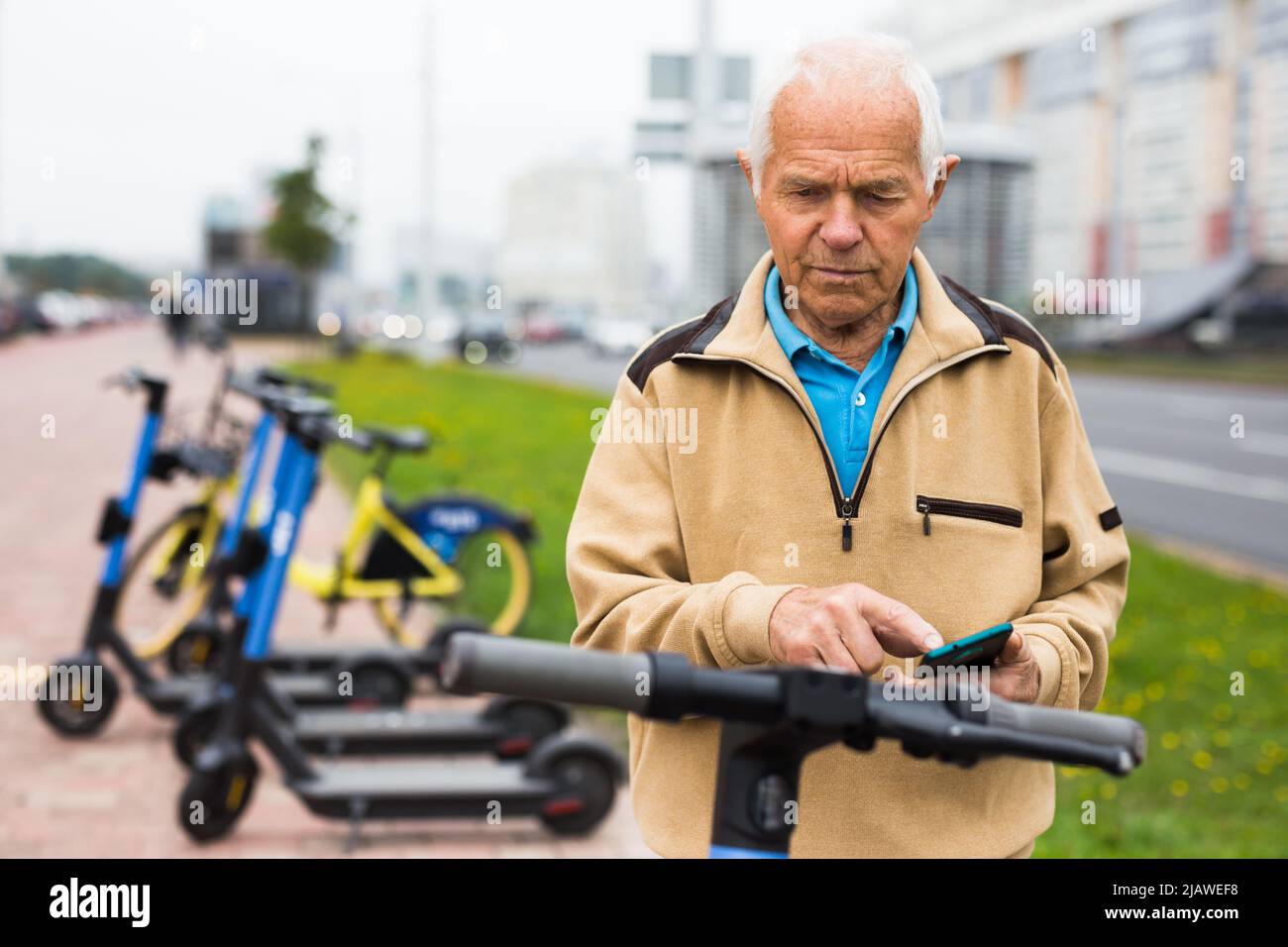 Old man using smartphone to activate e-scooter Stock Photo