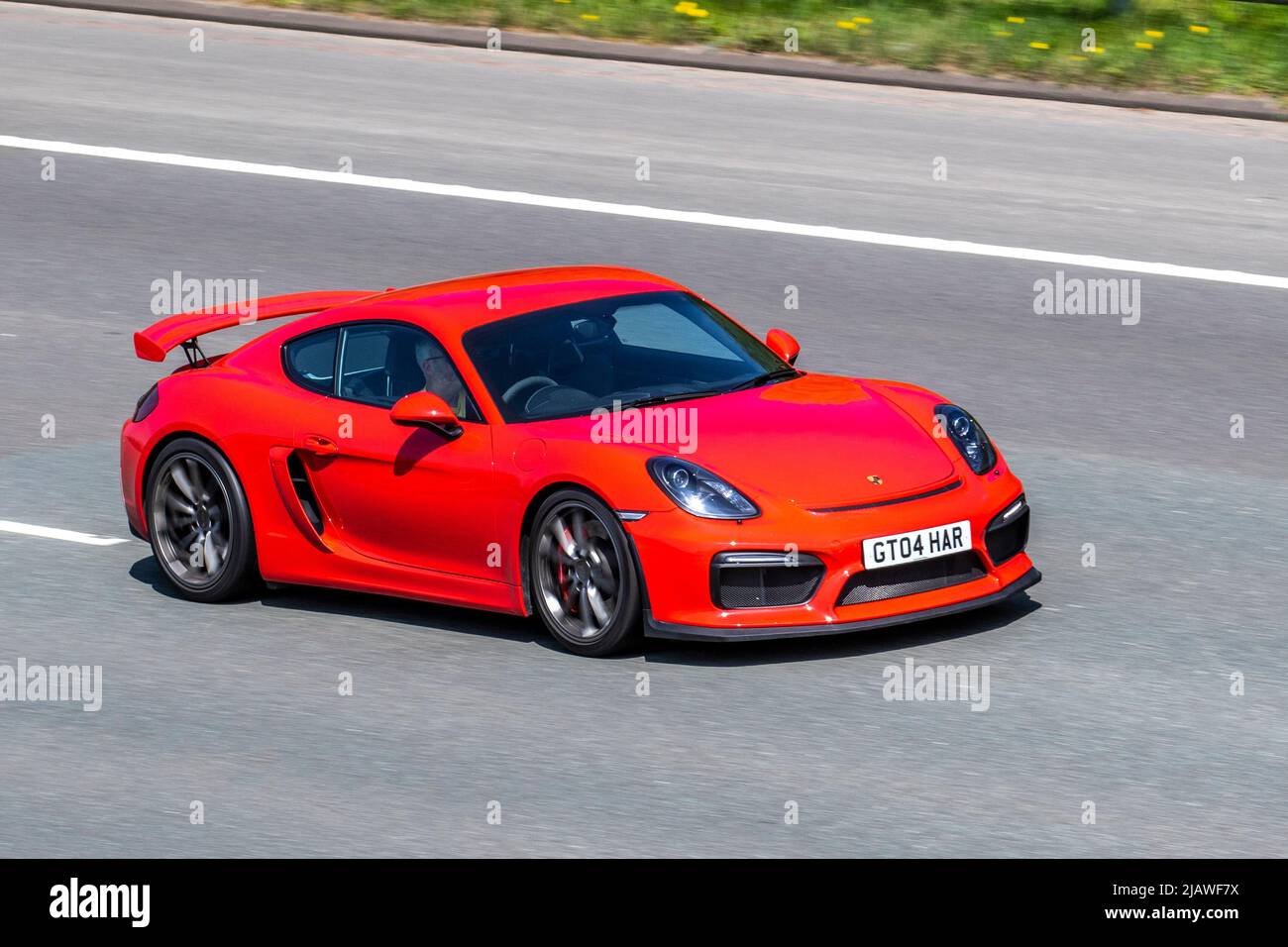 2015 red Porsche Cayman GT4 3800cc petrol coupe, driving on the M6 Motorway, UK Stock Photo