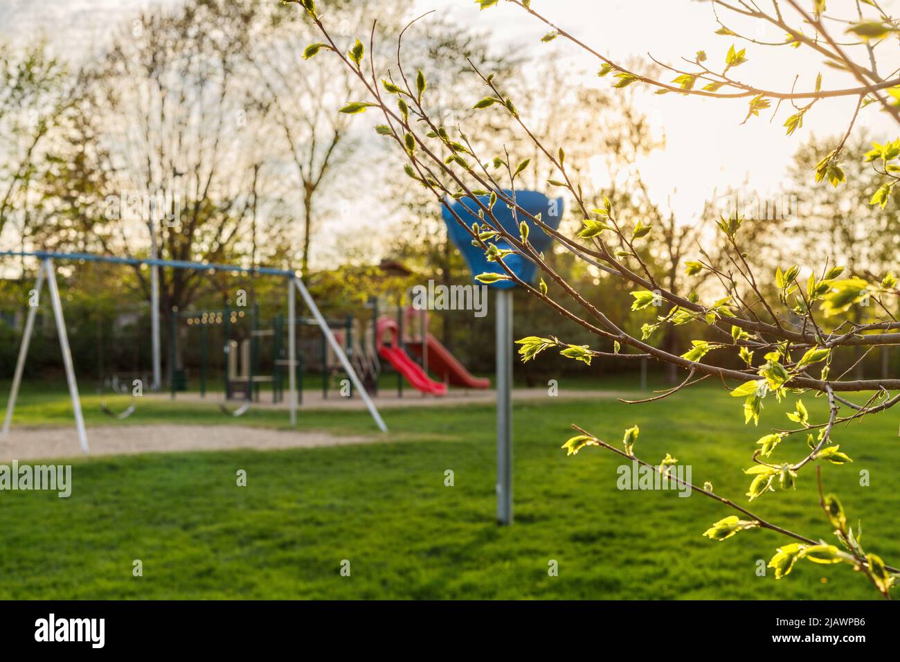 Playground in the local public park on a sunny spring day with green grass and trees. Stock Photo