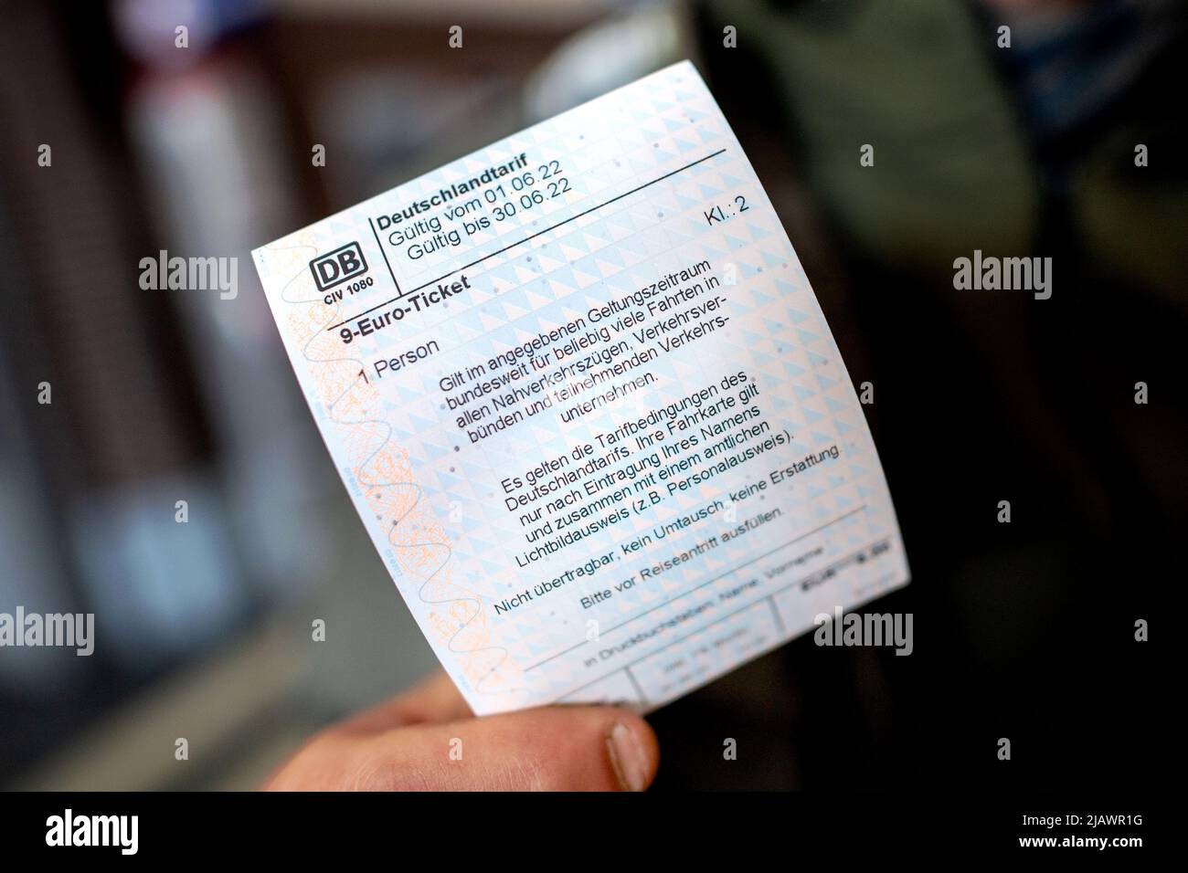 Oldenburg, Germany. 01st June, 2022. A young man holds a 9-euro Deutsche  Bahn ticket in his hand at the main train station. Travelers can use the 9- Euro-Ticket for journeys on local transport.