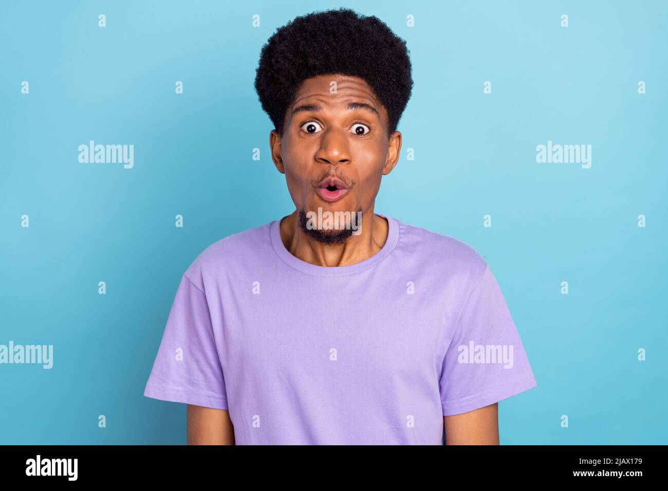 Photo of impressed pretty dark skin guy dressed purple t-shirt big eyes  isolated blue color background Stock Photo - Alamy
