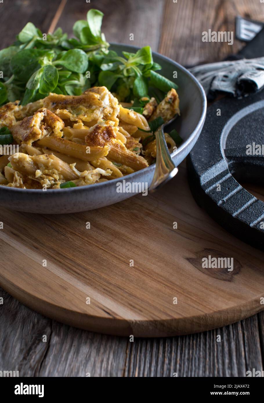Workout meal for dinner or lunch with pan fried whole wheat pasta, scrambled eggs and green salad served on wooden table background with copy space Stock Photo