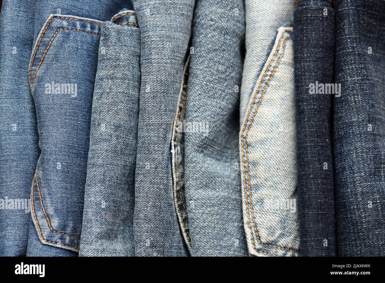 Many jeans in stack in wardrobe room. Row of pants denim jeans in