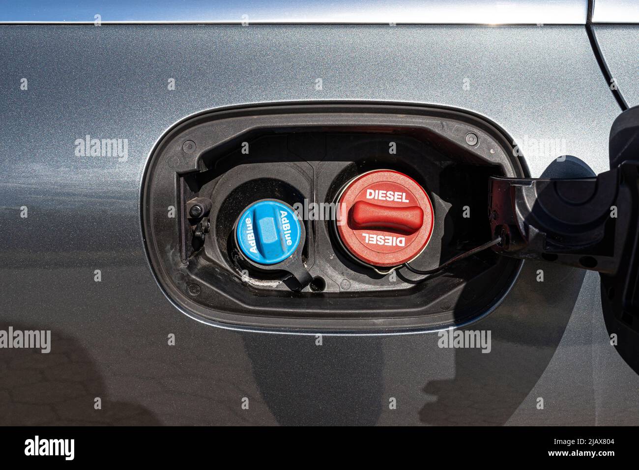 Fuel filler flap open with red diesel cap and blue adblue, the fuel filler caps are closed. Stock Photo