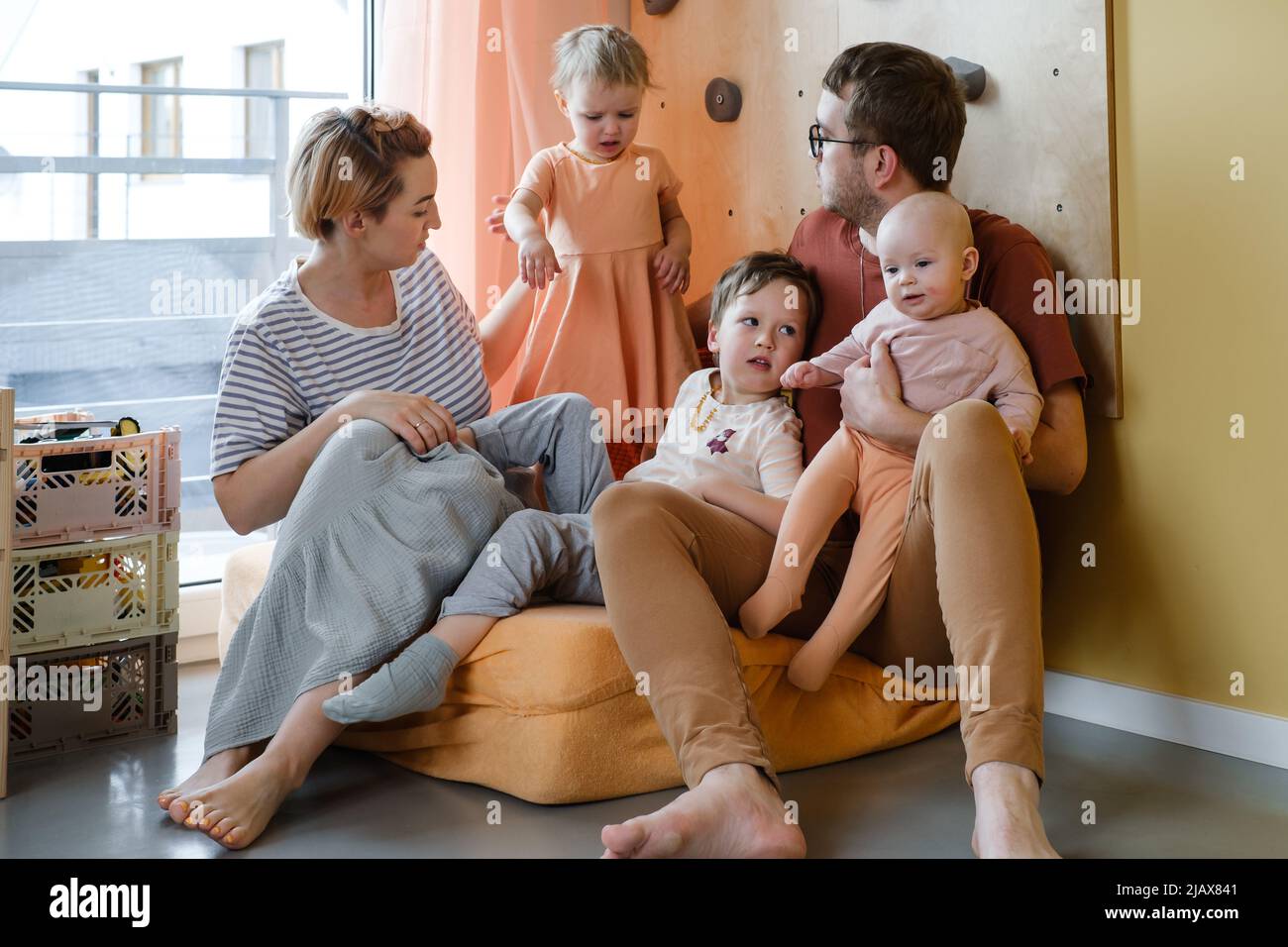 Big family in sunny play room. Parents playing with kids and toys. Happy time together with games. Mother father son daughters at modern colorful home Stock Photo