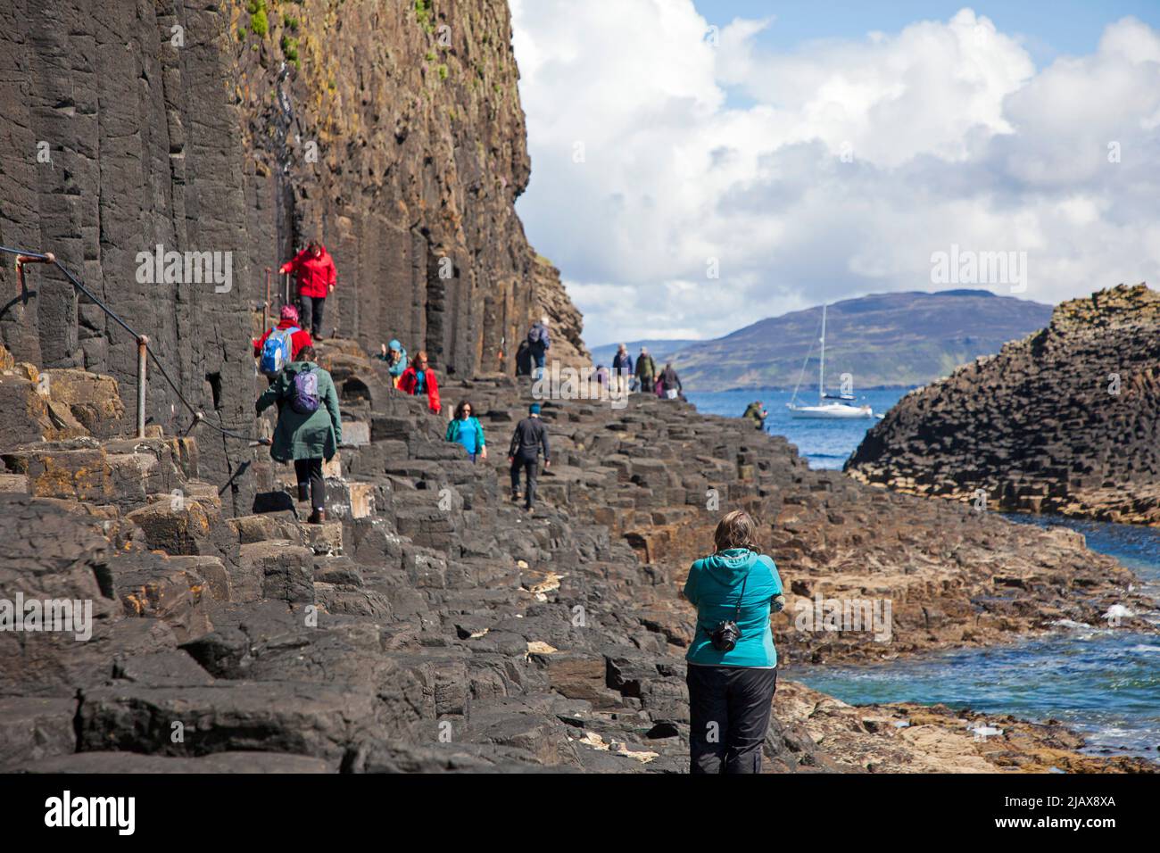 Tourists walking to and from Fingal's Cave on Staffa an island of the Inner Hebrides in Argyll and Bute, Scotland, UK Stock Photo
