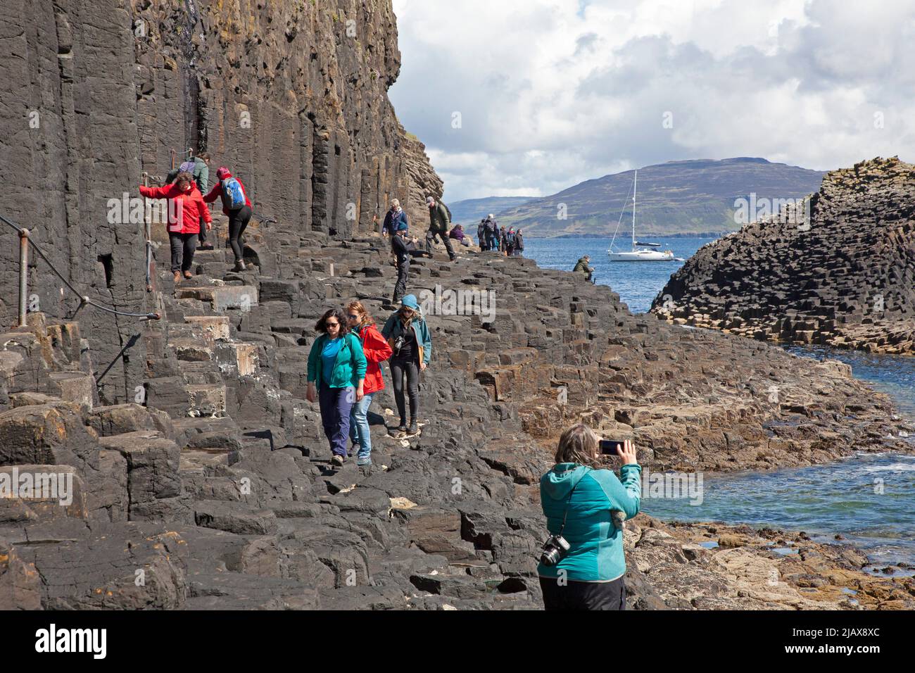 Tourists walking to and from Fingal's Cave on Staffa an island of the Inner Hebrides in Argyll and Bute, Scotland, UK Stock Photo