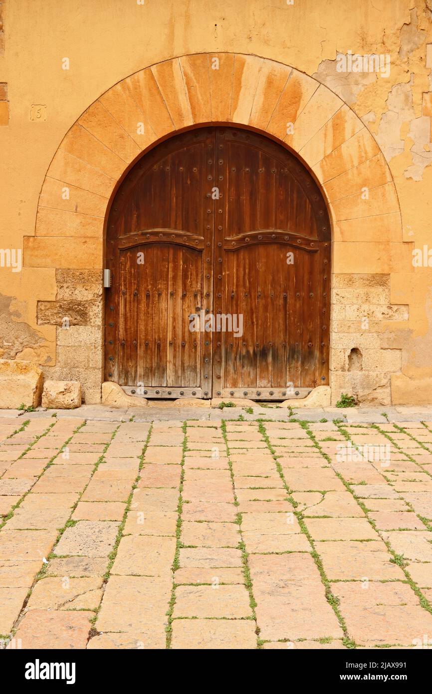 Old stone archway with worn wooden doors, Tarragona Stock Photo