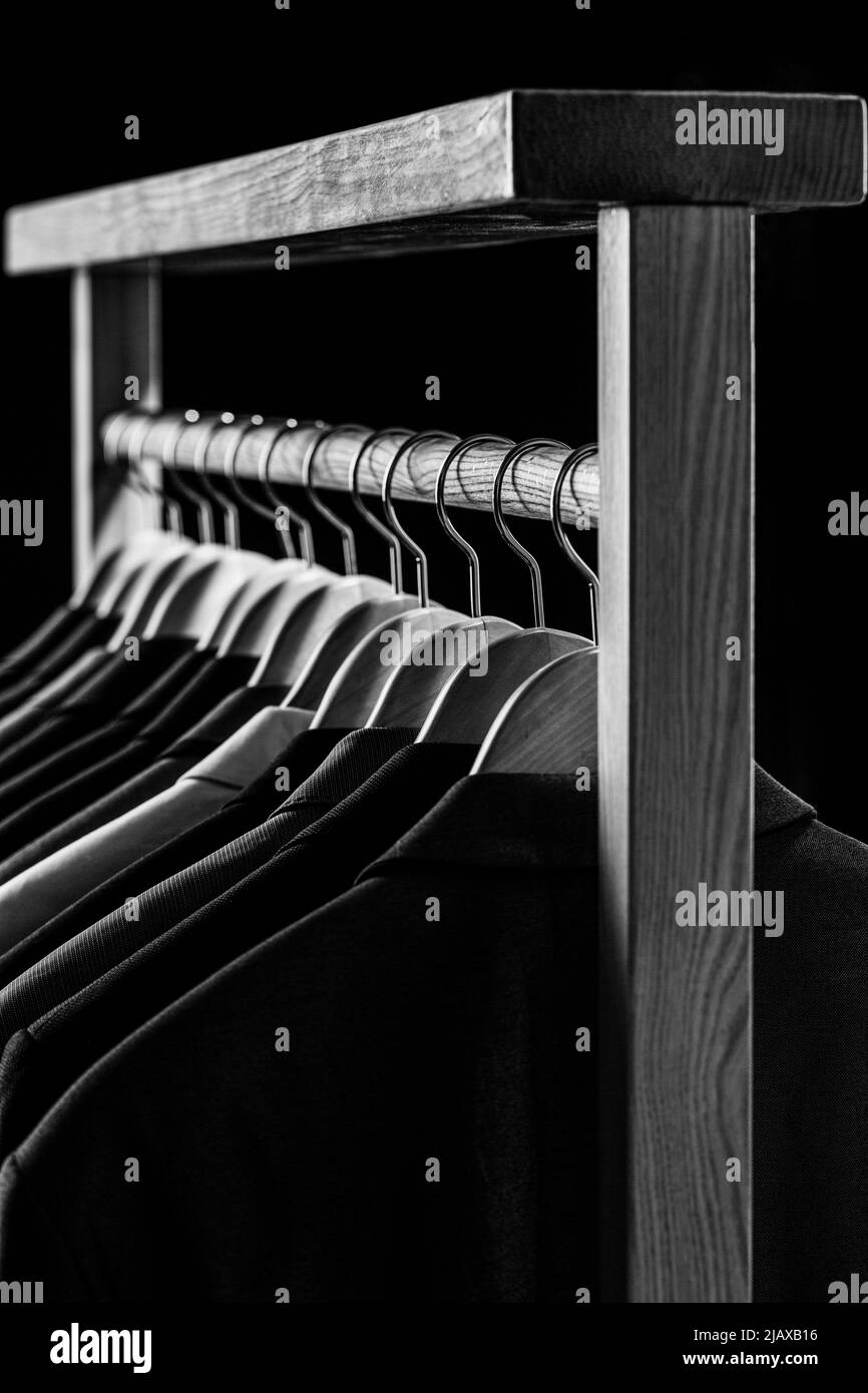 Mens shirts, suit hanging on rack. Hangers with jackets on them in boutique. Suits for men hanging on the rack. Mens suits in different colors hanging Stock Photo