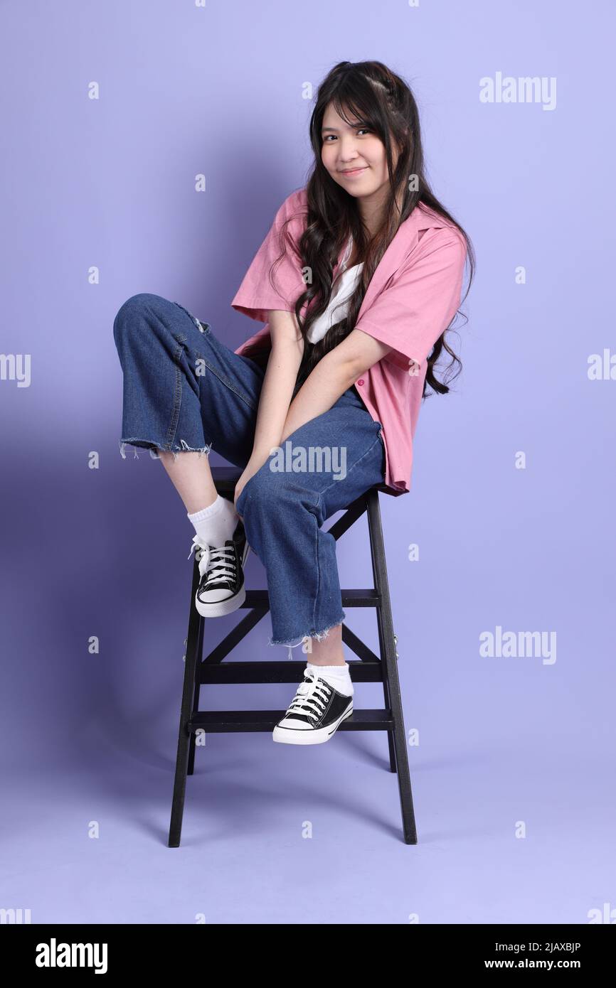 The cute young Asian girl with casual clothes sitting on the purple