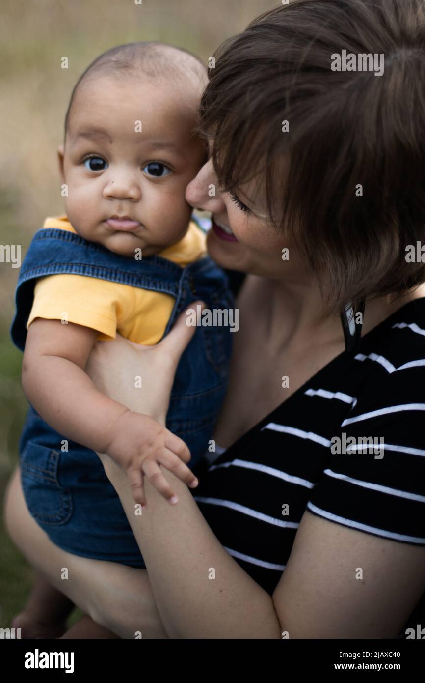 Mother holds and smiles at her mixed race baby boy Stock Photo