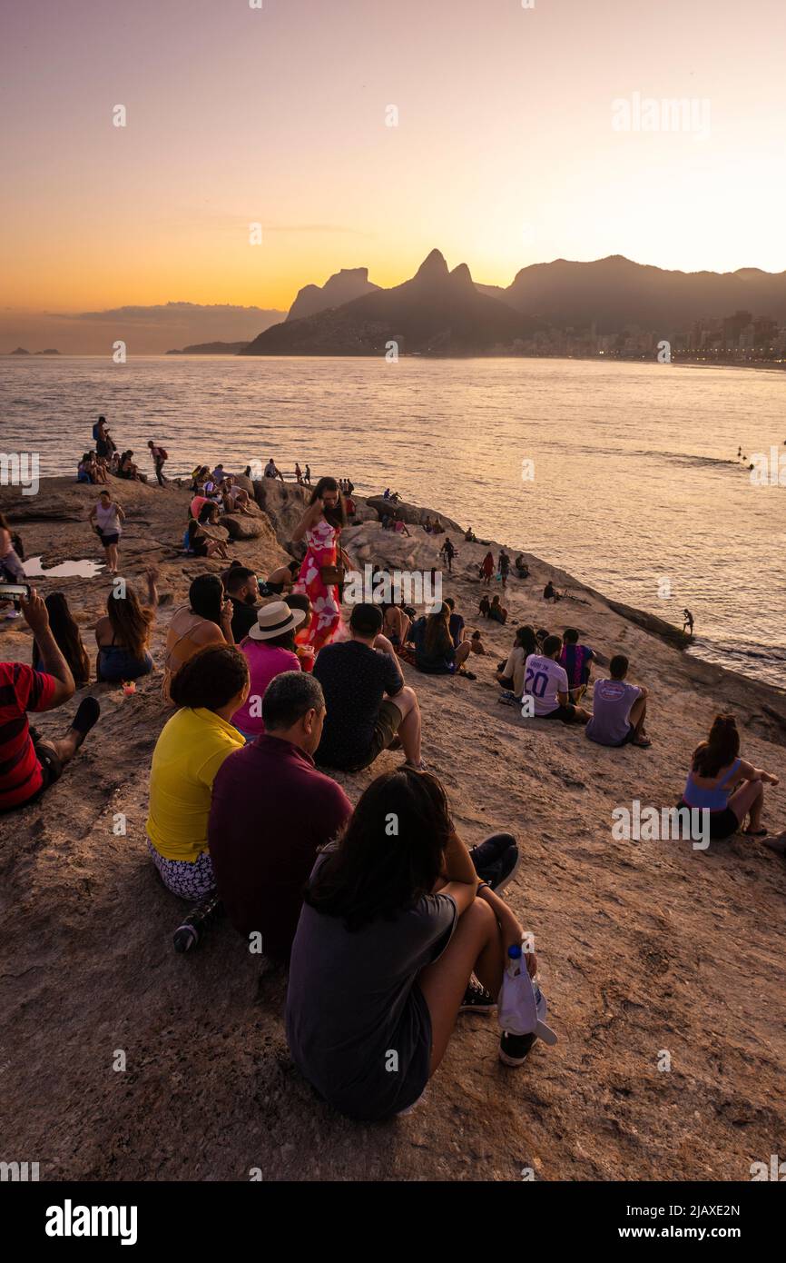 Beautiful view to people enjoying the sunset from the rocks in Ipanema Stock Photo