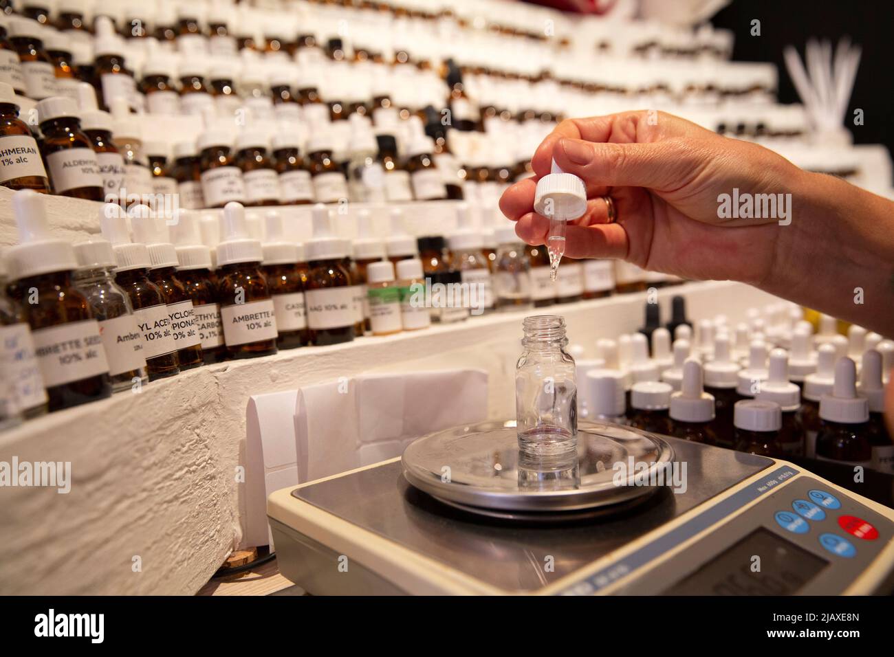 Jessica Buchanan, a perfume maker from Canada, creates a perfume at her perfumer’s organ displaying hundreds of vials of raw scent materials in her shop “1000 flowers” in Grasse, France on September 9, 2021. Jessica came to Provence in 2007 to attend the Grasse Institute of Perfumery. Today she has her own boutique in Grasse and is what's known in the business as a nose, or a nez in French. 'We do learn how to smell,' Buchanan says. 'That part of the brain really develops. It's like a muscle. It becomes more developed in a perfumer than in a regular person who's not paying attention to scents Stock Photo