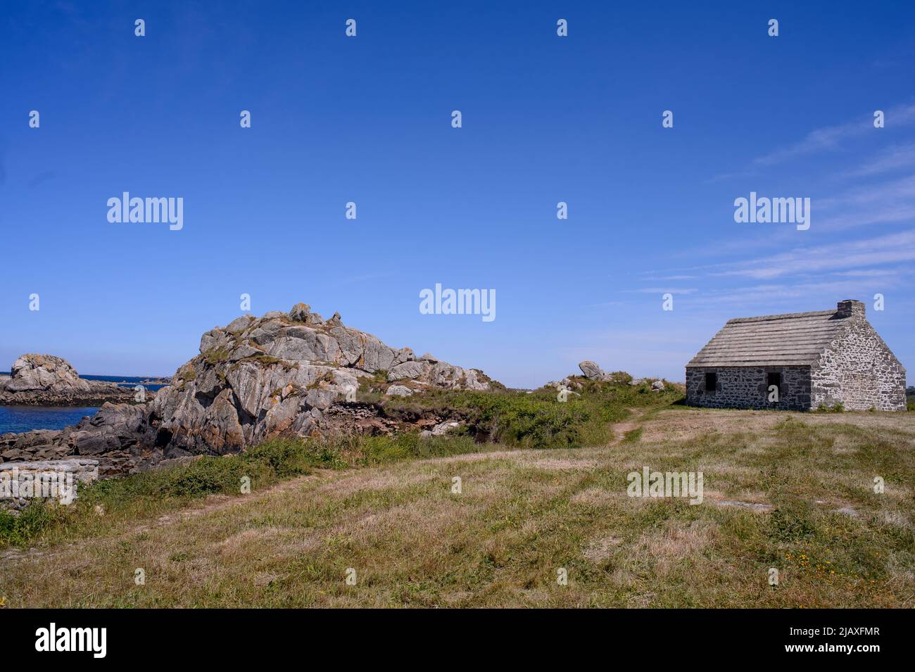 Typical Breton stone house. This old fisherman's house on a promontory facing the sea seems to have been there as long as the rock that protects it. Stock Photo
