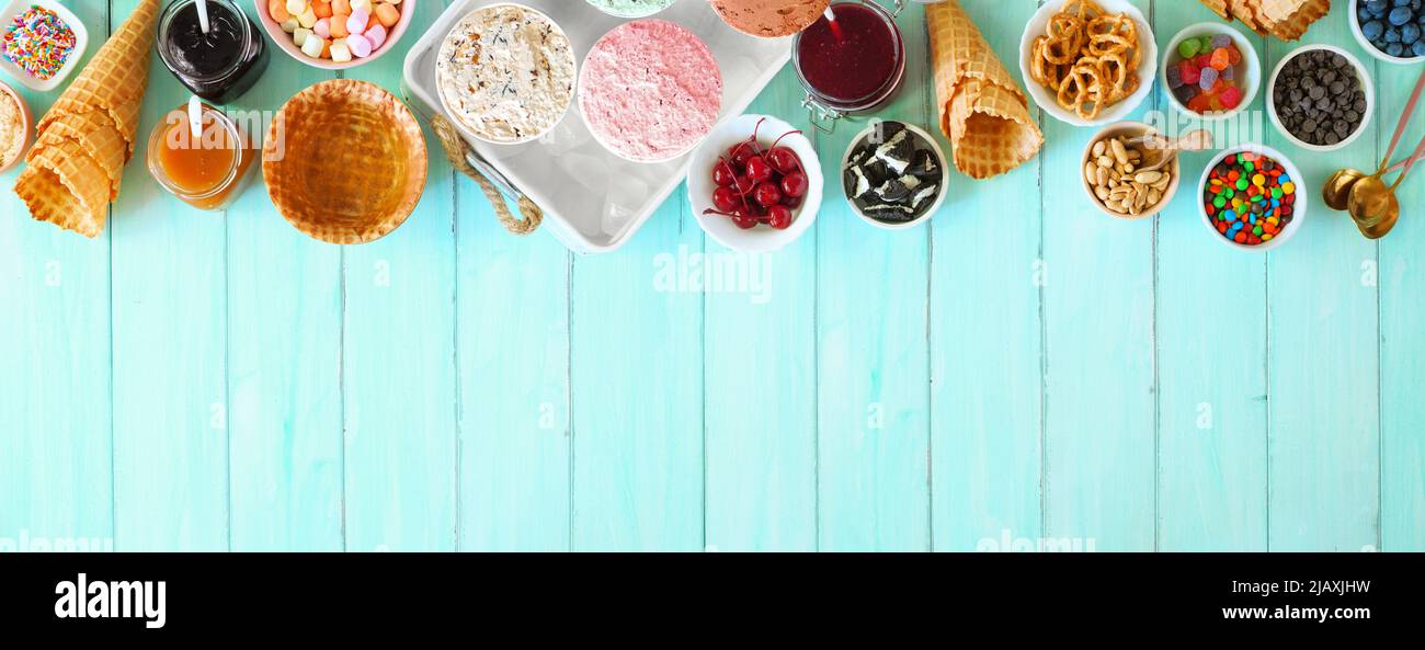 Summer ice cream buffet with assorted of flavors and sweet toppings. Above view table scene on a blue wood background. Stock Photo