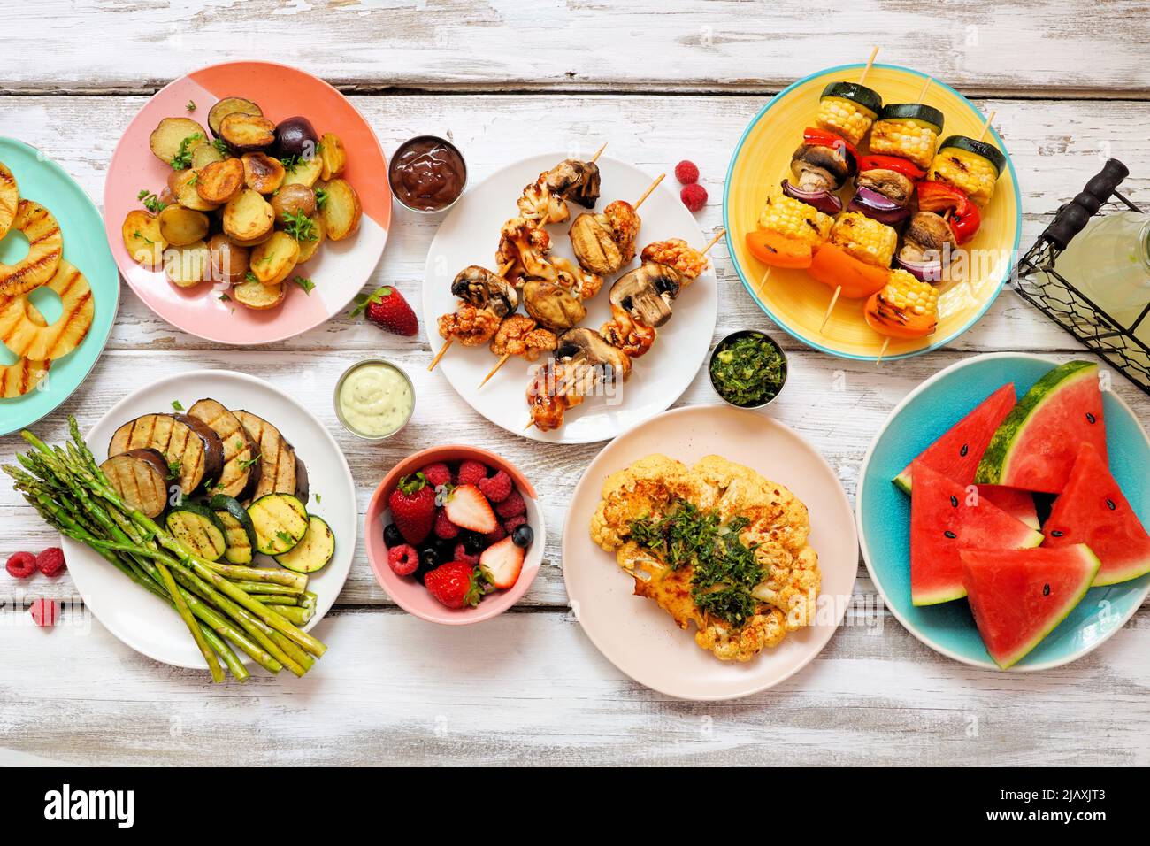 Healthy plant based summer bbq table scene. Top view on a white wood background. Fruit, grilled vegetables, skewers, cauliflower steak and lemonade. M Stock Photo