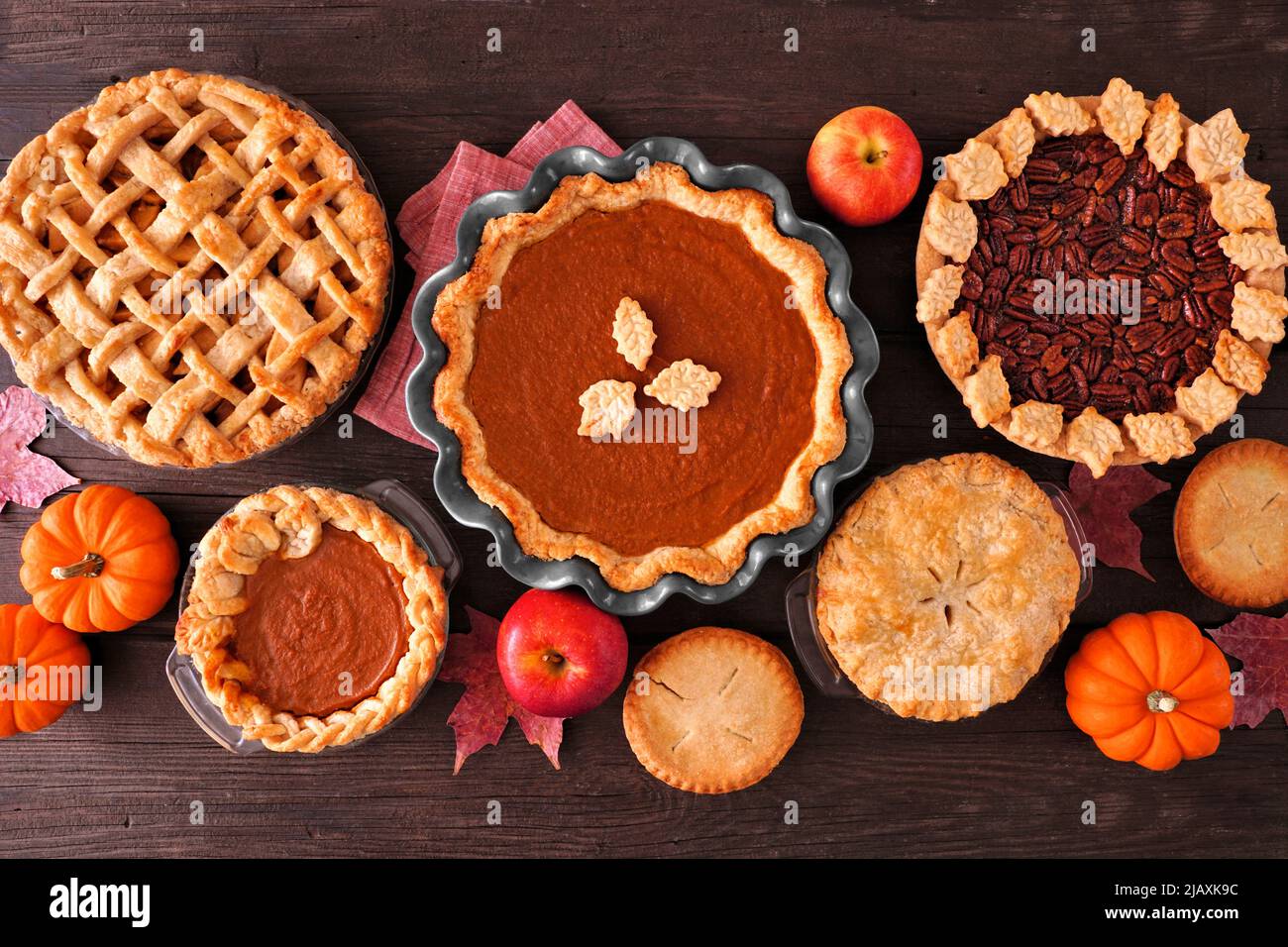 Assortment of homemade fall pies. Apple, pumpkin and pecan. Top down view table scene on a dark wood background. Stock Photo