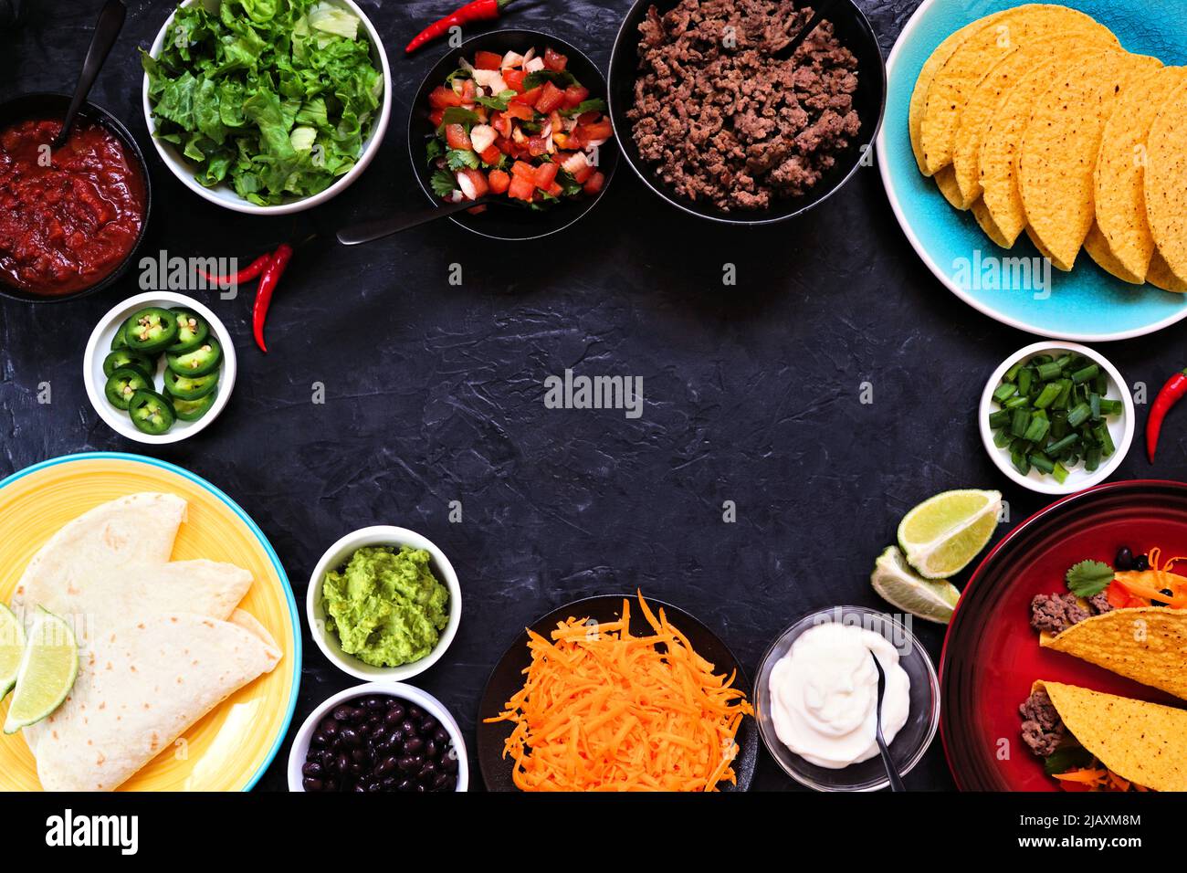 Taco bar frame with assorted ingredients. Above view on a dark slate background. Mexican food buffet. Copy space. Stock Photo