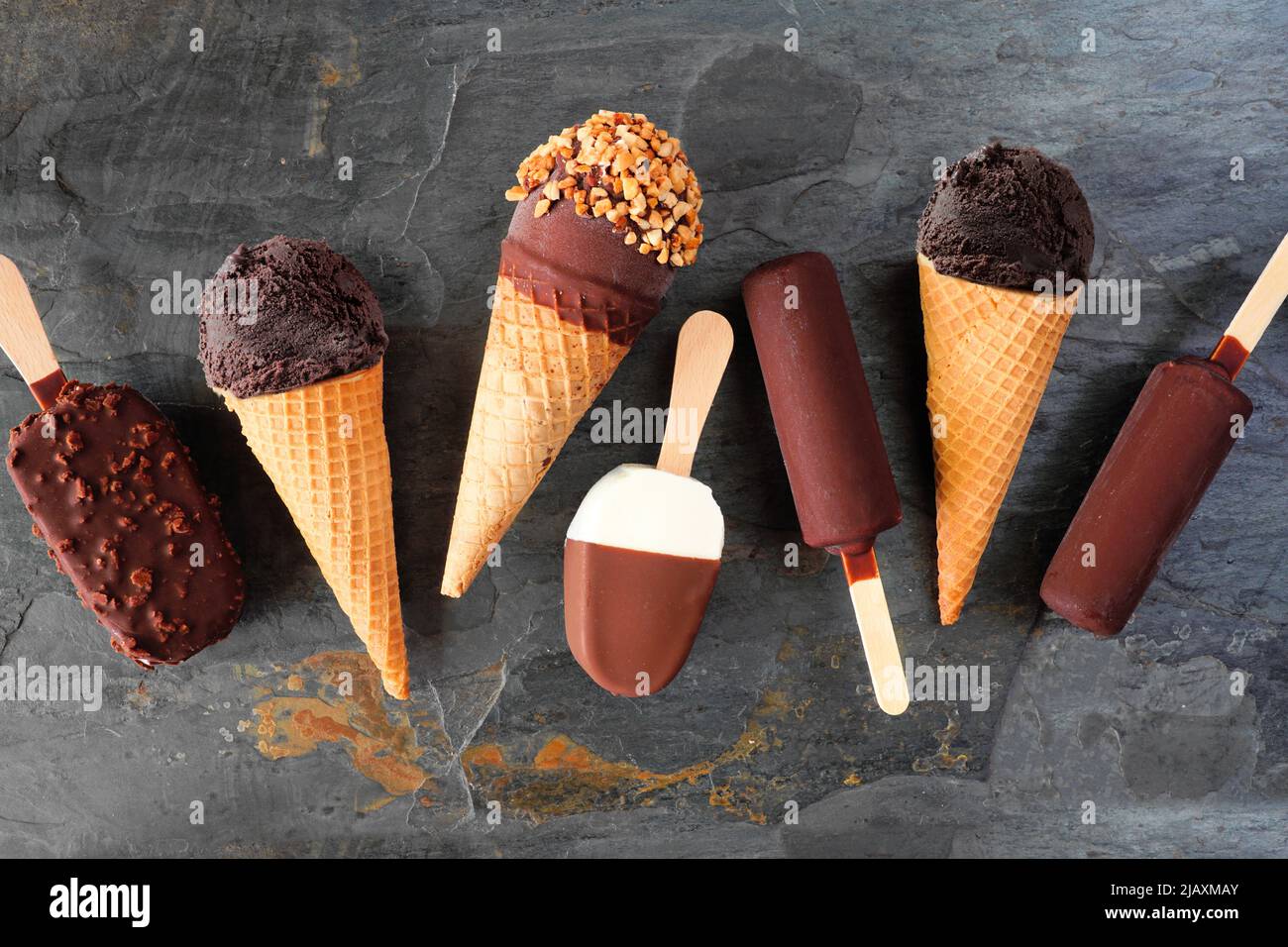 Variety of chocolate ice cream desserts. Overhead view scattered on a dark slate background. Stock Photo