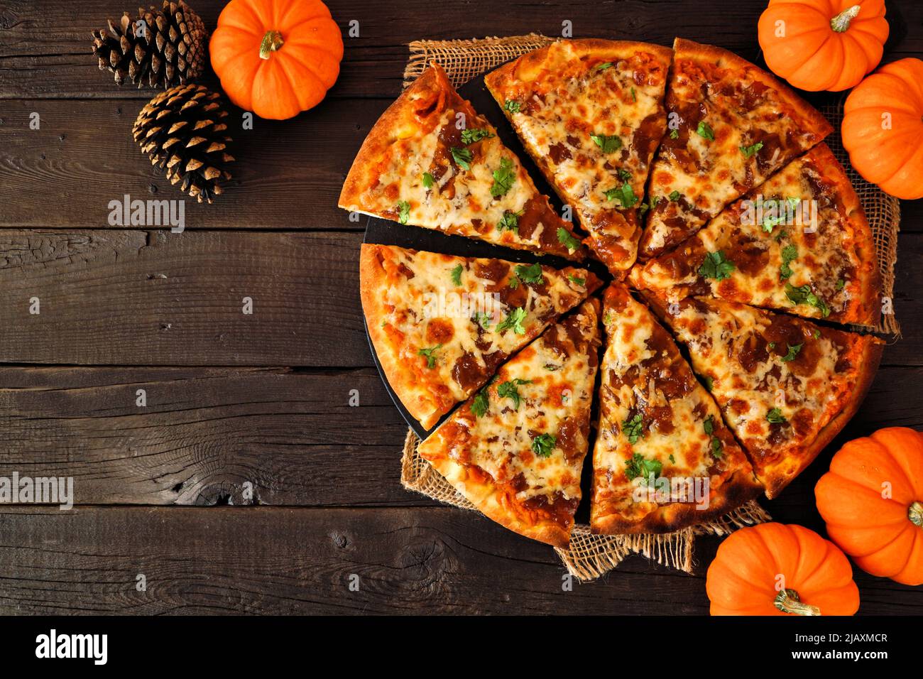 Fall pizza with pumpkin sauce, gouda and caramelized onions. Above view on a dark wood background. Copy space. Stock Photo