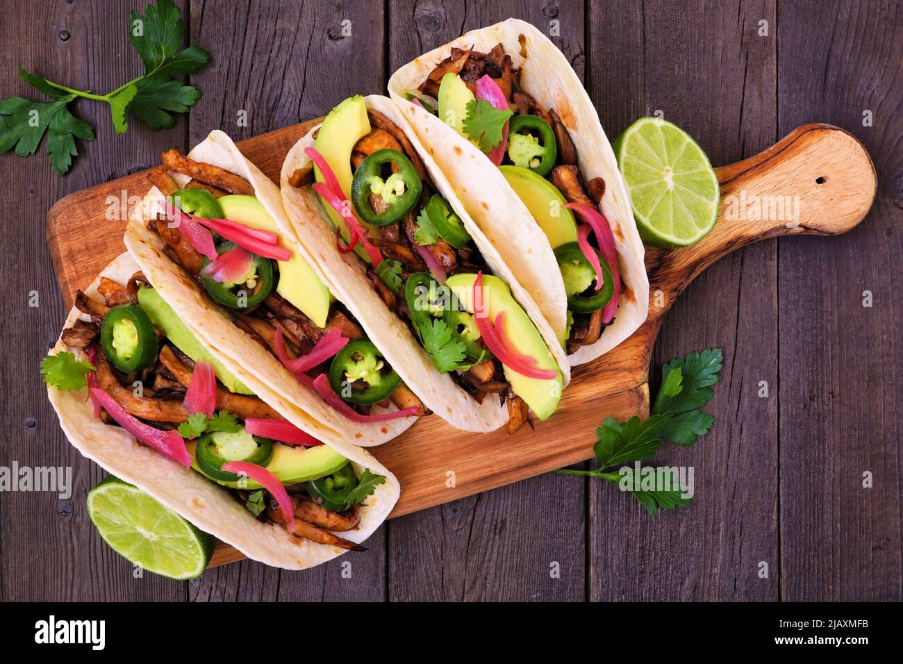Vegan mushroom tacos. Serving board, above view on a dark wood background. Healthy eating, plant based meat substitute concept. Stock Photo