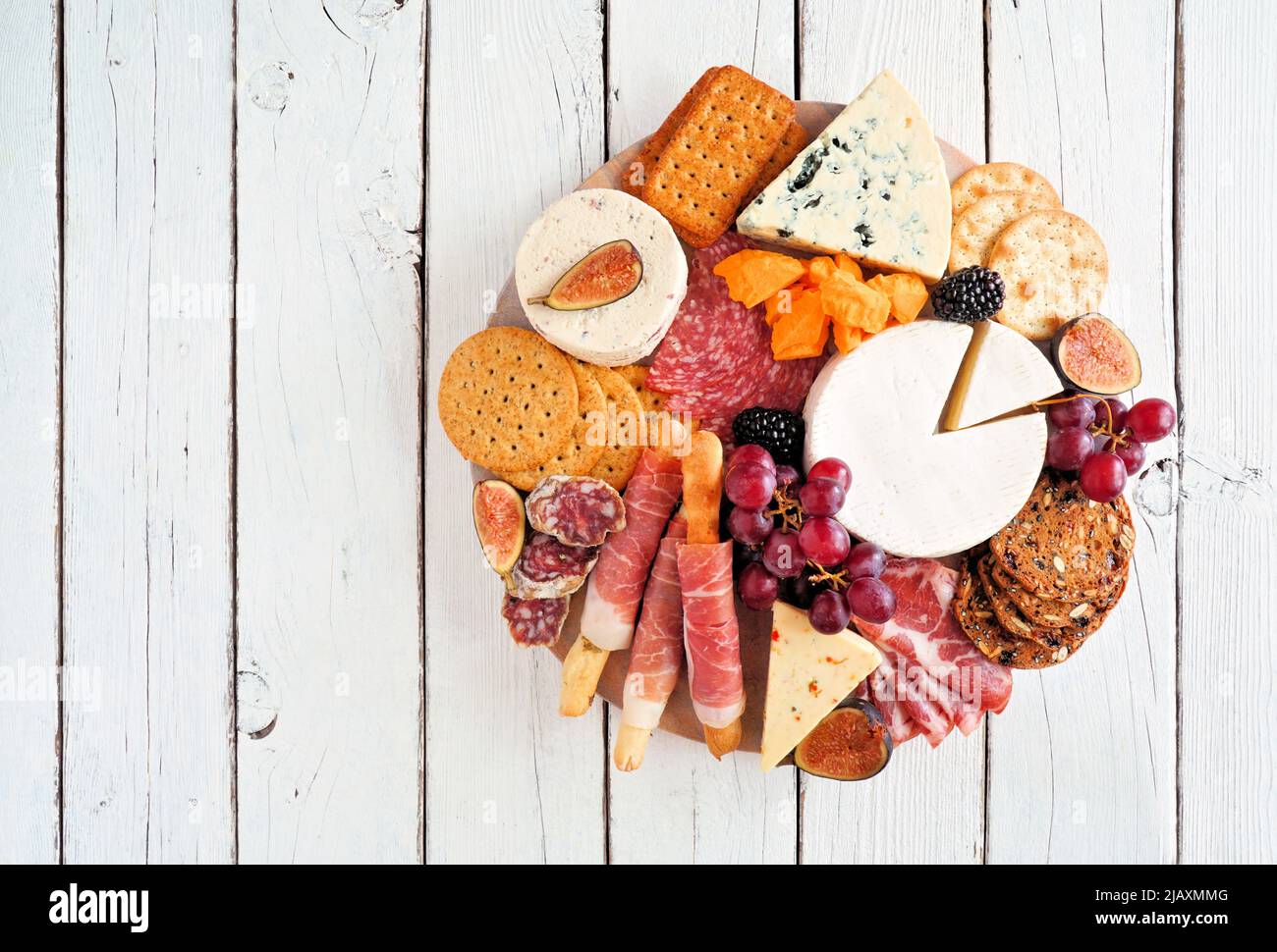 Charcuterie platter with different meats, cheeses and appetizers. Top view on a white wood background. Stock Photo